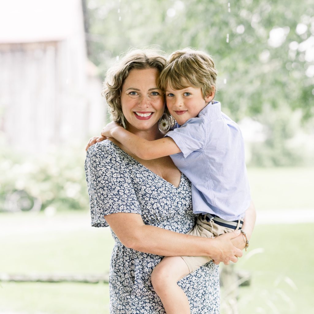Portrait of Mother holding boy child on her hip on porch of house in the rain in summertime