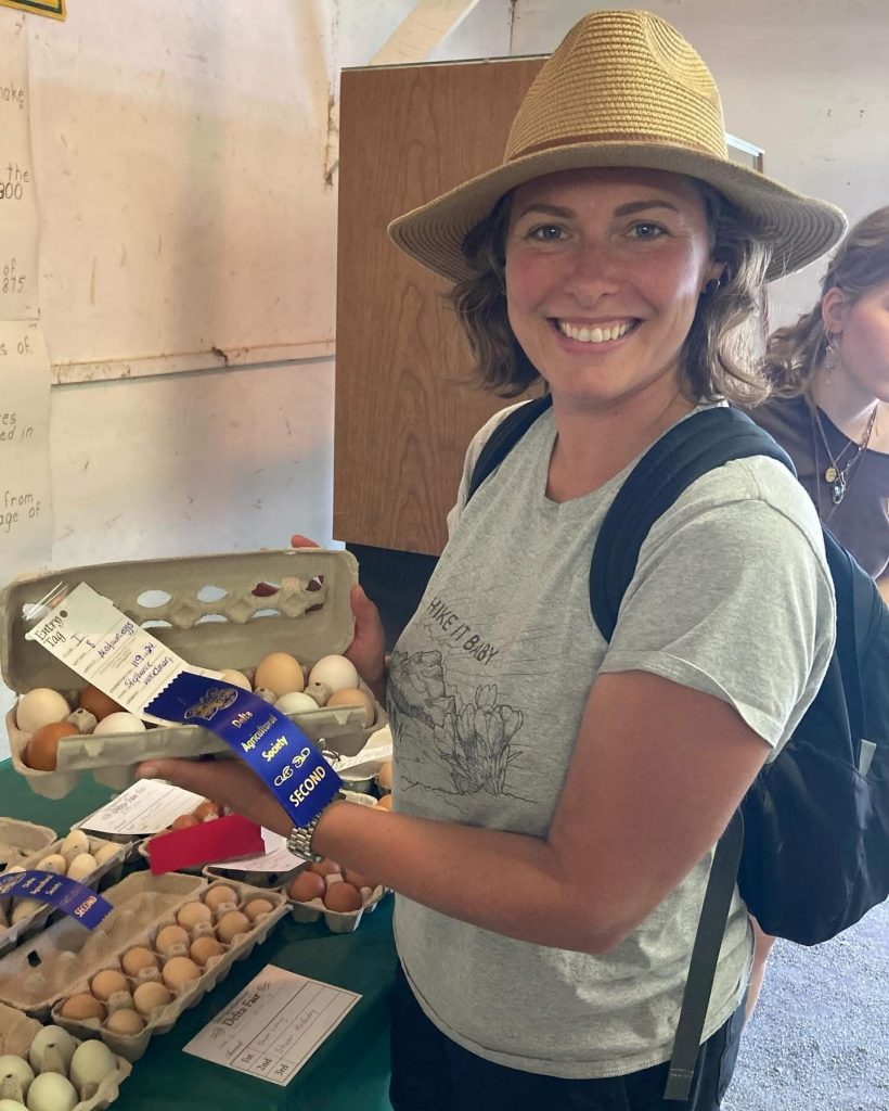 Woman with straw hat holding award winning eggs at agricultural fair