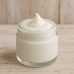 Clear Jar containing white natural toothpaste sitting on wooden countertop
