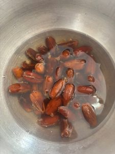 Medjool dates soaking in hot water in a metal bowl
