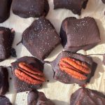 Close up of homemade Healthier Chocolate covered salted "caramels" made with dates. Some have pecans on top of them and all have sea salt.
