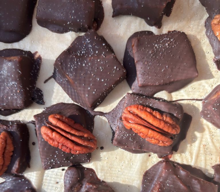 Close up of homemade Healthier Chocolate covered salted "caramels" made with dates. Some have pecans on top of them and all have sea salt.