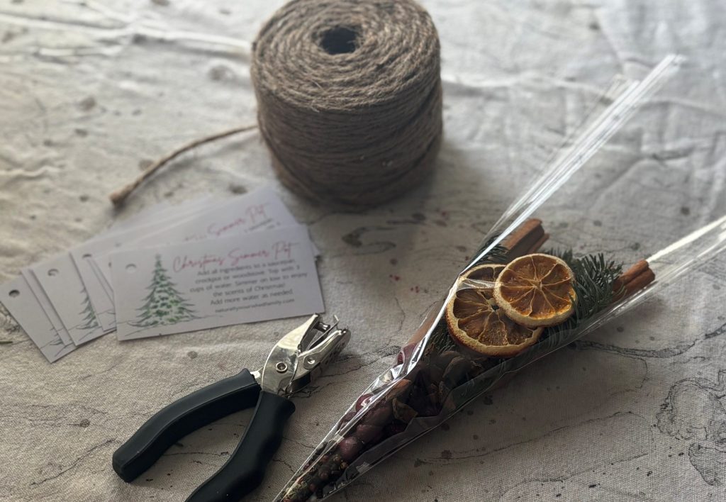 Close up of jute twine, gift tags, hole punch, and unfinished simmer pot bag