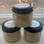 Three clear glass jars on window sill containing homemade natural peppermint cocoa deodorant