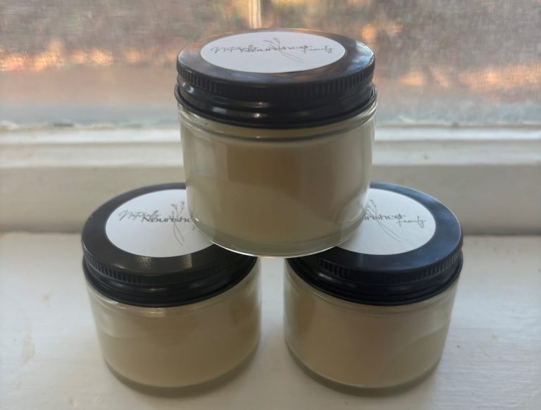 Three clear glass jars on window sill containing homemade natural peppermint cocoa deodorant