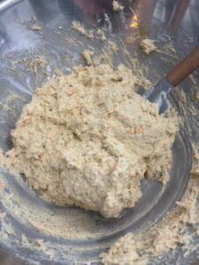 Close up of savoury cheese and herb muffin sticky batter in stell bowl with spatula