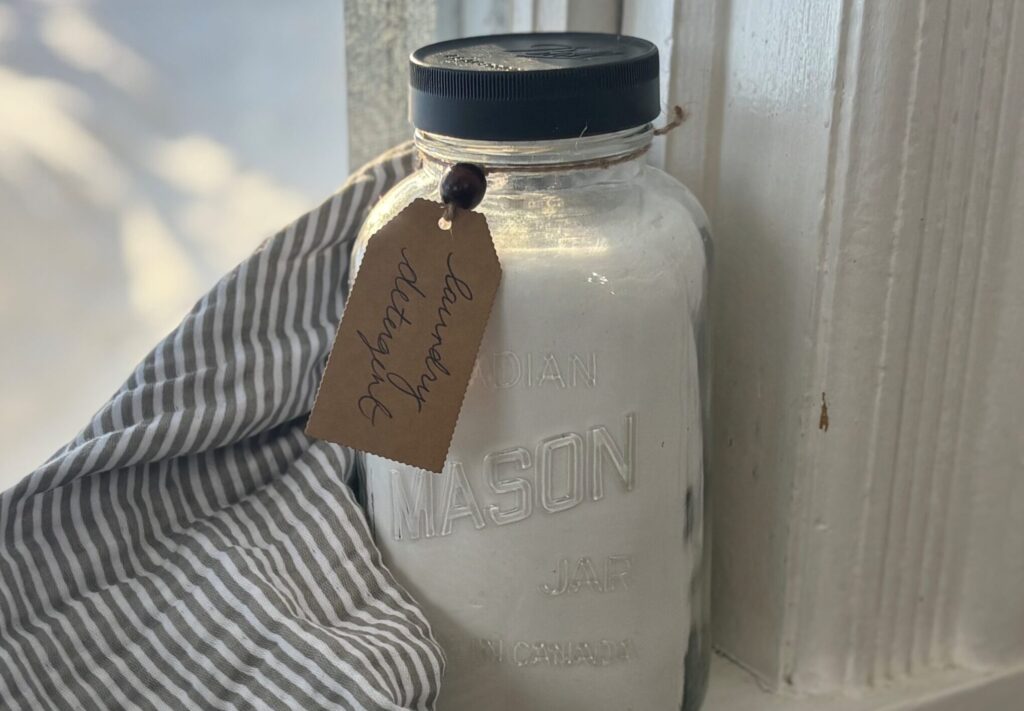quart sized mason jar on a windowsill filled with homemade powdered laundry detergent