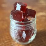 glass jar of deep red homemade gummy candies sitting on wooden table
