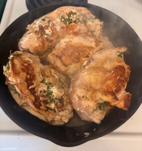 Seared and cooked stuffed chicken breast in cast iron pan on stovetop