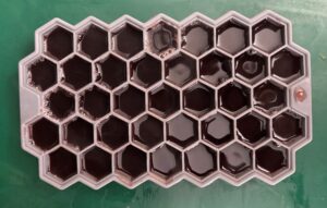 grey silicone beehive shaped ice tray mold filled with gelatin mixture sitting on green countertop