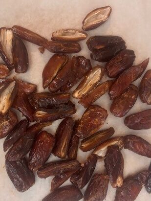 pitted and sliced in half, medjool dates on a piece of white parchment paper