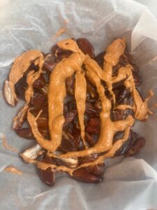 Medjool dates with drizzled natural peanut button on top of bleached parchment paper