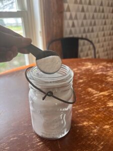 Homemade dishwasher powder with scoop on table in home