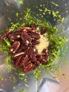 scapes, pecans, salt, pepper, lemon juice and parmesan cheese being blended in a high speed blender