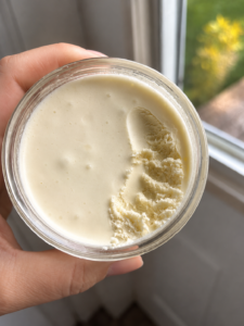 whipped face cream in clear glass jar held by a woman