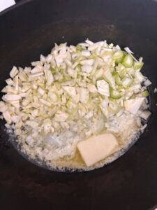 cooking up onions, celery, and butter for base of chowder in a black dutch oven on stovetop