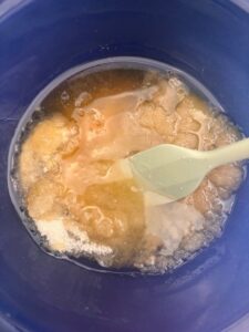 ingredients for sugar scalp scrub in blue glass bowl and light green spatula